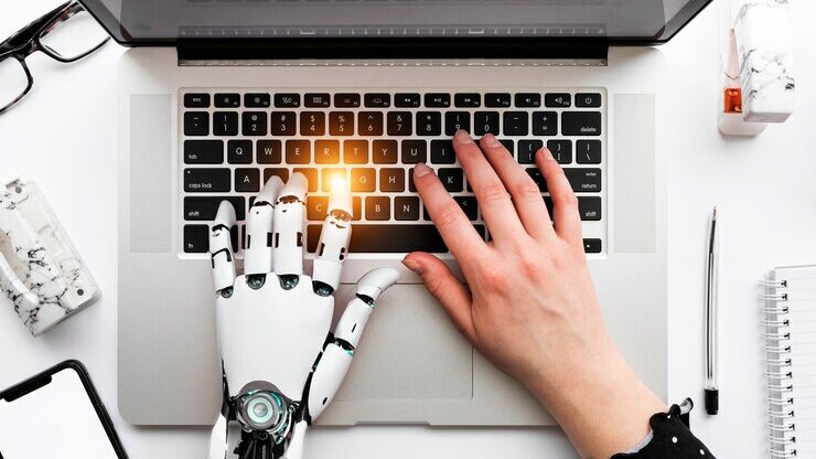 due mani di cui una robotica che scrivono al computer