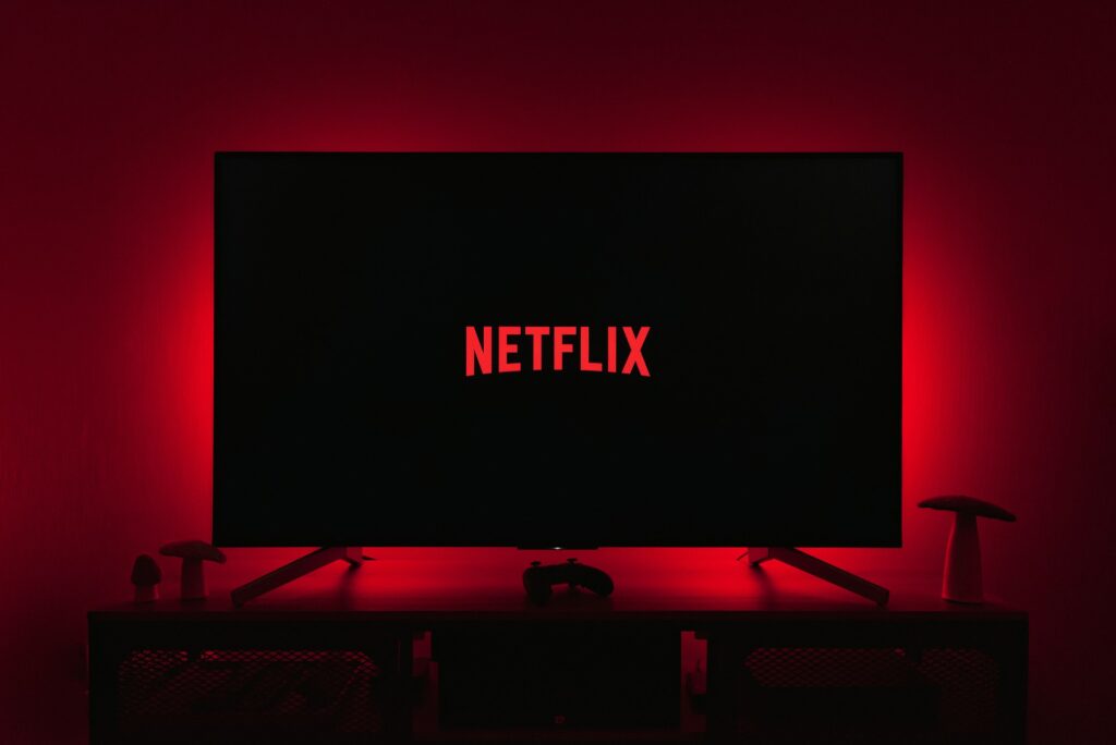 Immagine di un televisore con luci LED rosse dietro. nello schermo della televisione compare il logo di NETFLIX